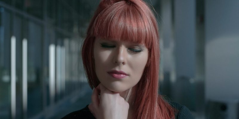 Close up of red haired woman with eyes closed and hand under her chin