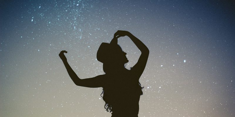 Silhouette of a woman looking up at the stars in the night sky