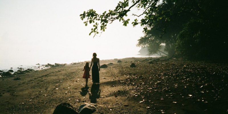 Mother and daughter walking hand in hand towards the distance that is not visible