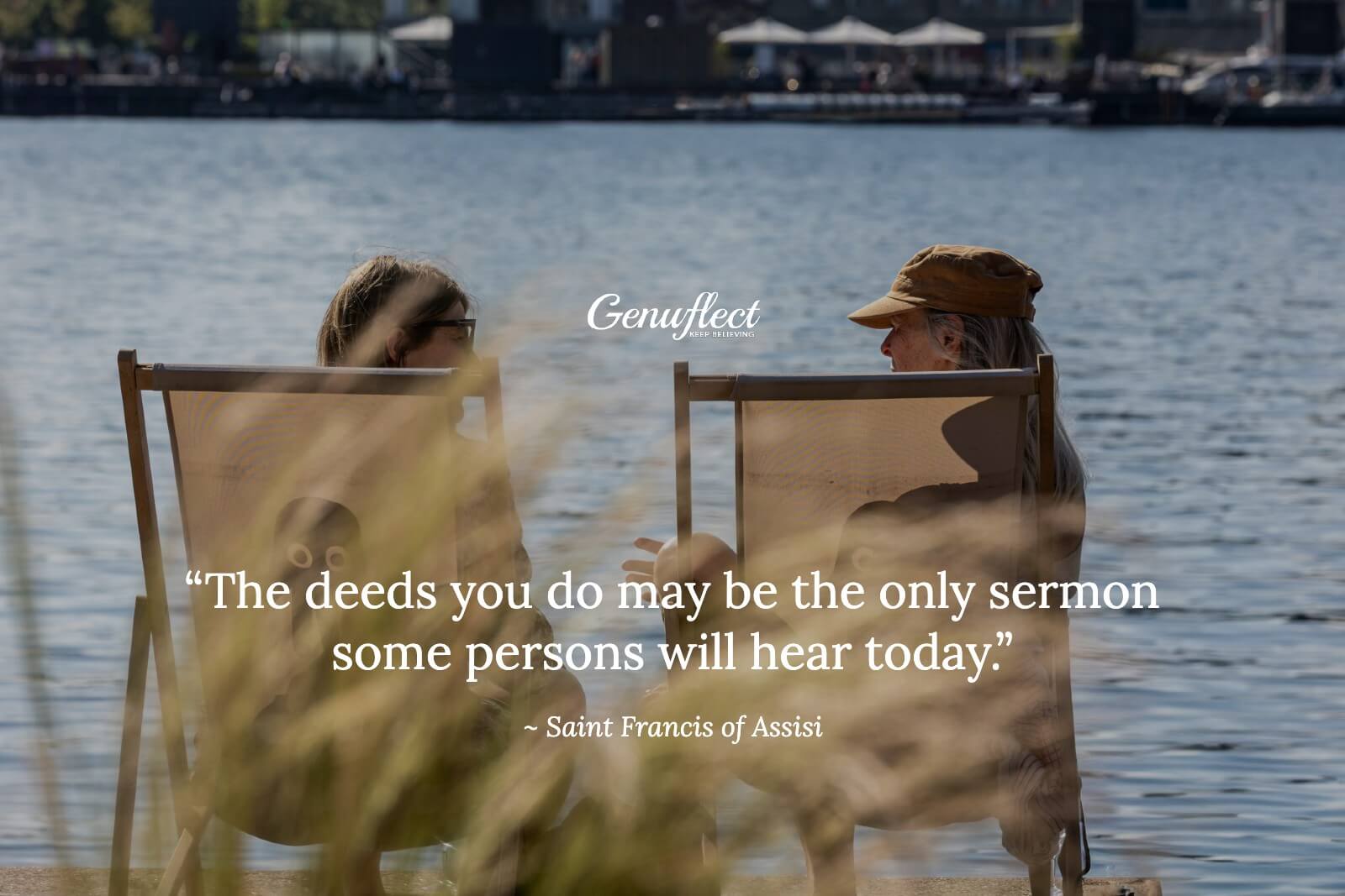Two people sitting on the shore of a lake talking
