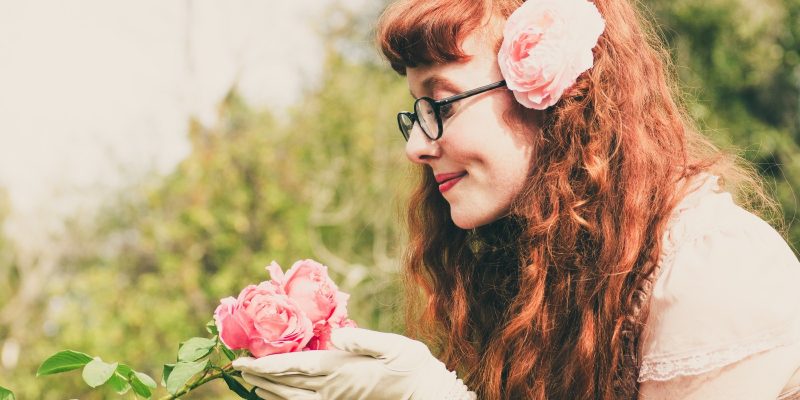 Woman smiling and admiring pink roses in her hands