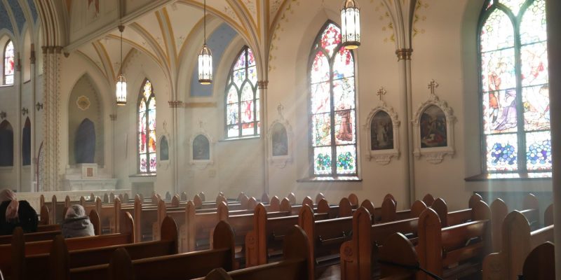 Pews in a mostly empty Catholic Church with just a few people