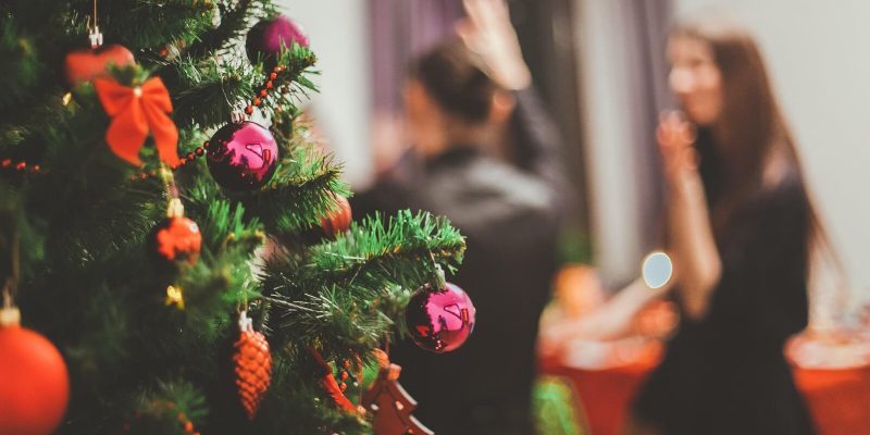 Close up photo of Christmas tree in the foreground with man and woman in the background