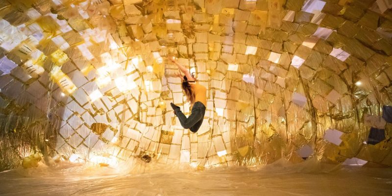 Side view of woman jumping in the air against a golden background