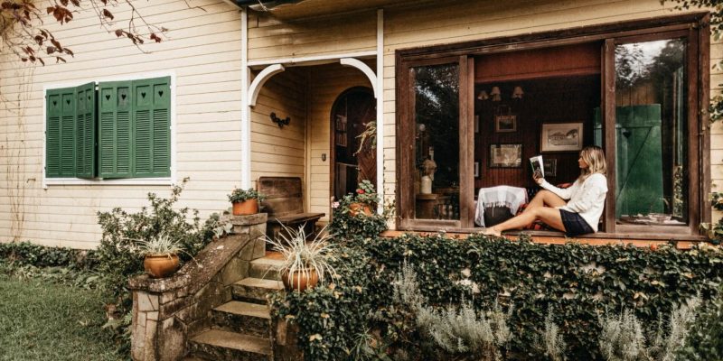 Woman sitting outside on her front porch reading a book