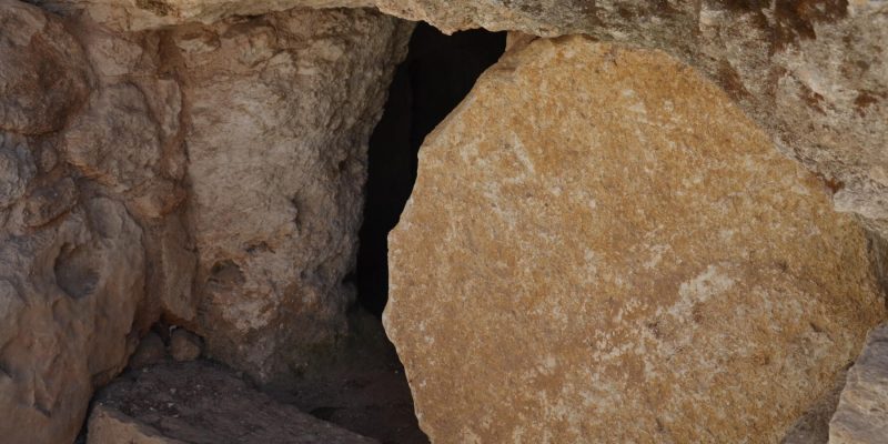 Dark tomb hewn in rock with a stone cracked open