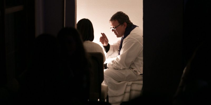 A Priest hearing the confession of a woman