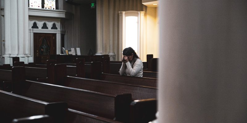 Woman kneeling in prayer in a Cathedral