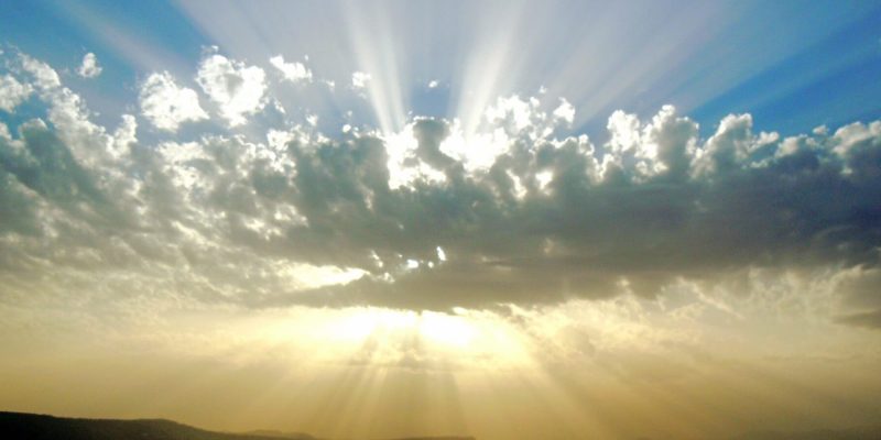 Rays of sun coming out from behind a cloud over the ocean