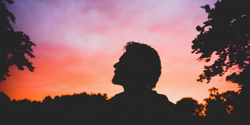Silhouette of man against a pink and orange sky