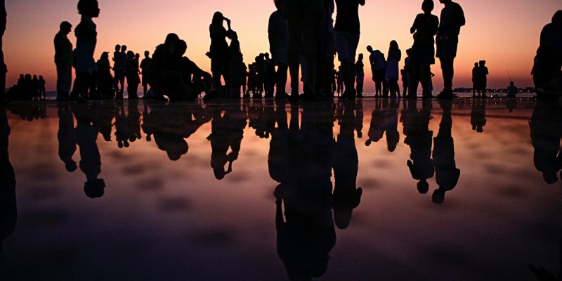people at dusk with reflection in water