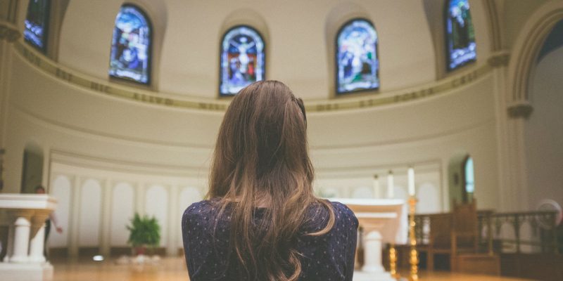 Genuflect - girl praying in church