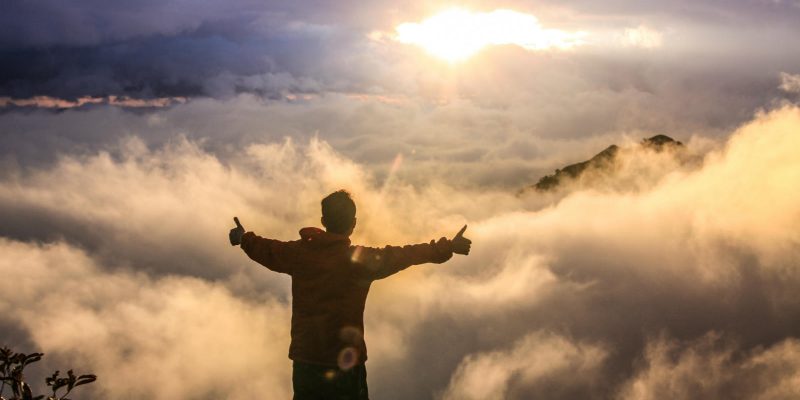 Man standing above clouds with his arms outstretched