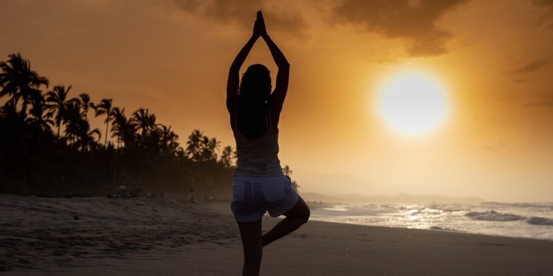 Woman in yoga pose at beach at sunrise