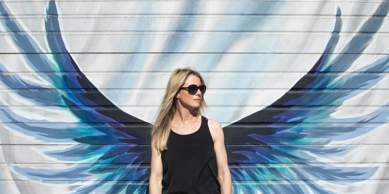 Woman standing in front of a wall with angel wings painted on it