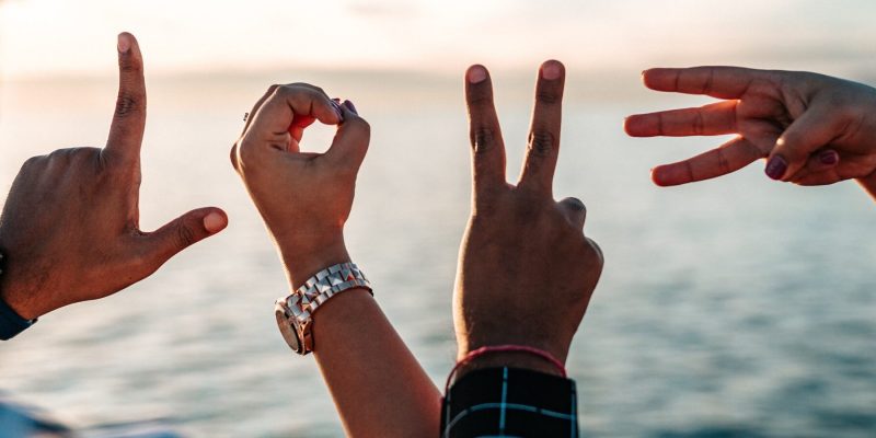 Four hands forming letters to spell the word LOVE