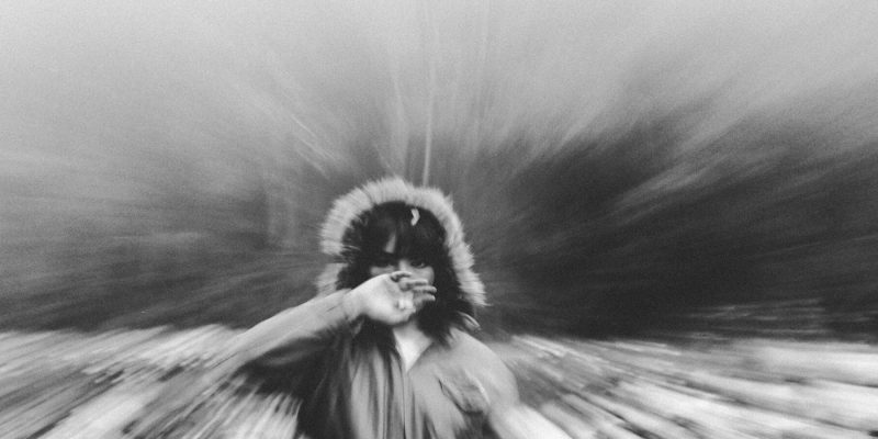 Black and white image of a person with hand over mouth and background blurred.